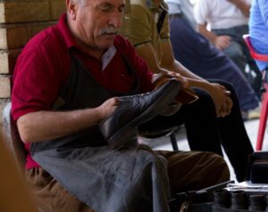 An experienced shoemaker finishing and polishing a leather shoe by hand
