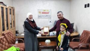 Zeinat Abu Samour, head of Zein al-Din Abed Basic School, presenting a plaque to NABOLY manager Fadl Al-Natsheh during a student visit