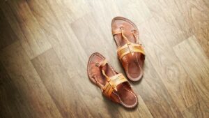 A pair of brown leather T-strap sandals on a tiled floor